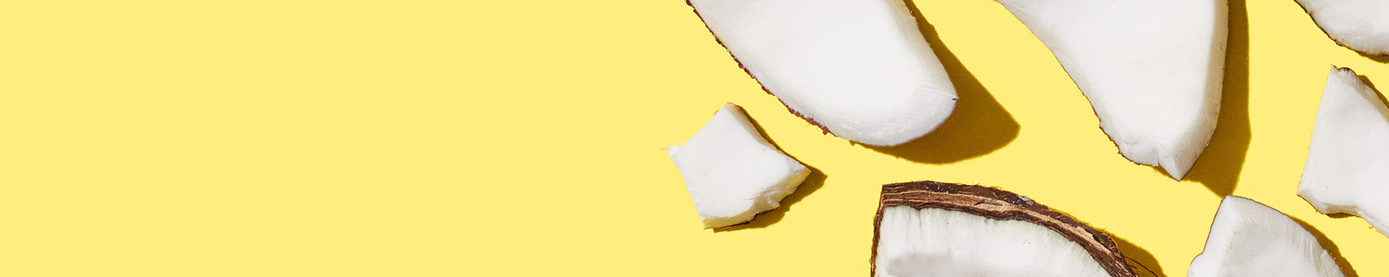 Up close shot of broken up coconut pieces on a yellow background. 