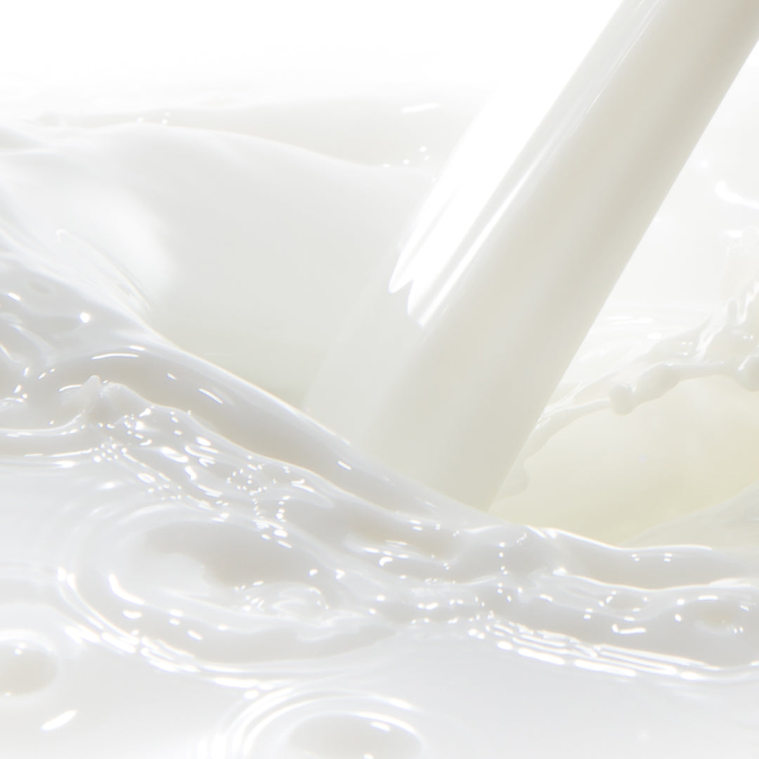 Close up shot of goat milk being poured into more milk, causing a ripple. 